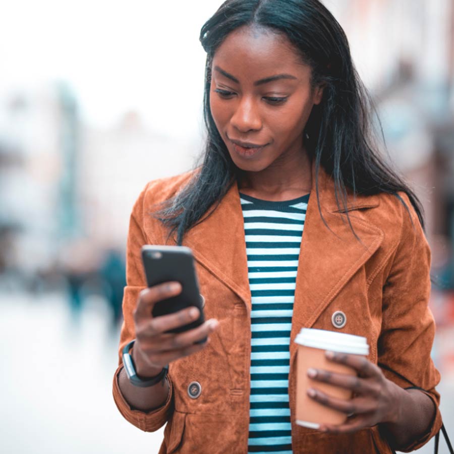 Woman holding phone and cup of coffee on the city streets